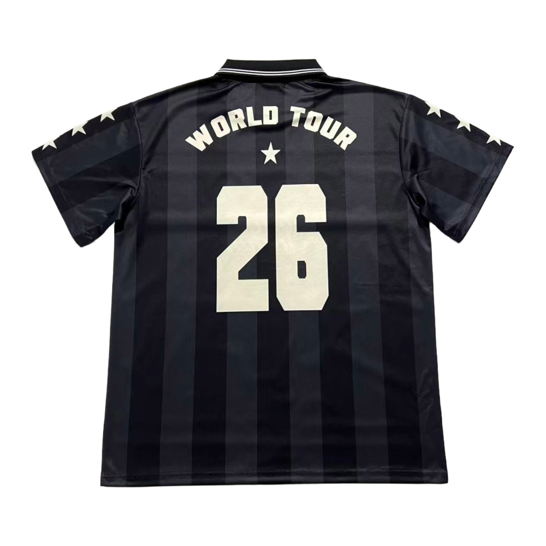 Back view of a black vertically striped 5 seconds of summer soccer jersey with 'WORLD TOUR' and the number '26' printed in cream on the back, featuring cream stars on the sleeves.